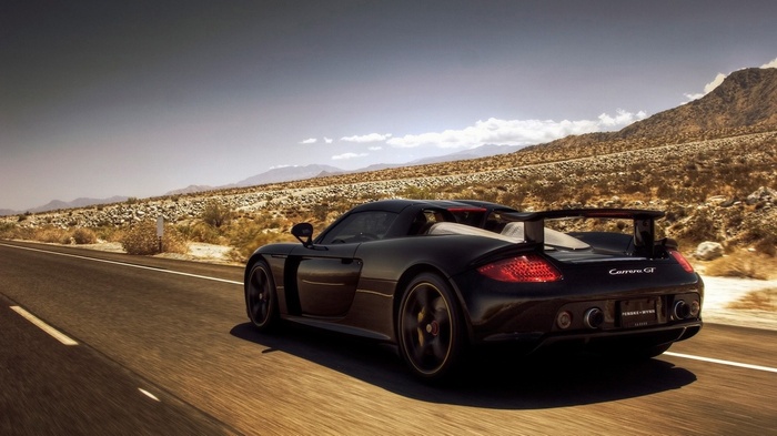 Black Porsche Carrera GT driving on a desert road