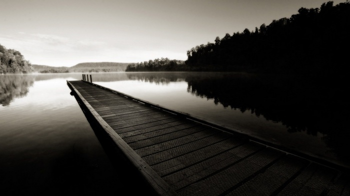 Sepia toned lake with a wooden pier and forest