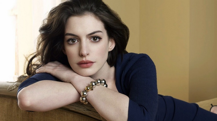 Anne Hathaway posing on a couch