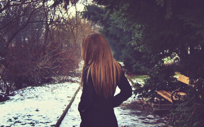 Woman in black coat in snowy park