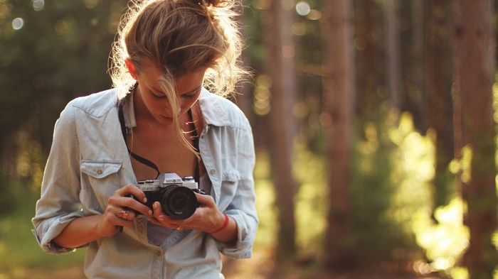 Woman holding a Minolta camera in a forest