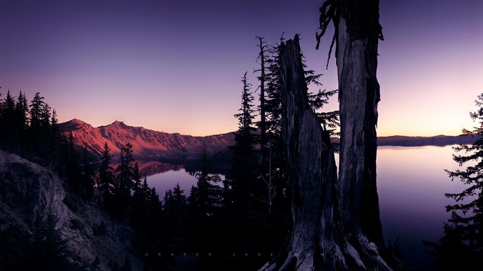 Crater Lake at sunset with mountains and trees