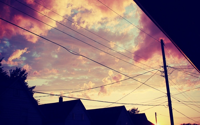 Sunset over houses with power lines and clouds