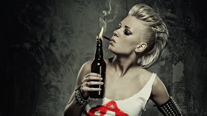 Punk woman smoking a cigarette with a burning bottle