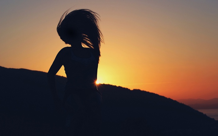 Silhouette of a woman with hair flying at sunset