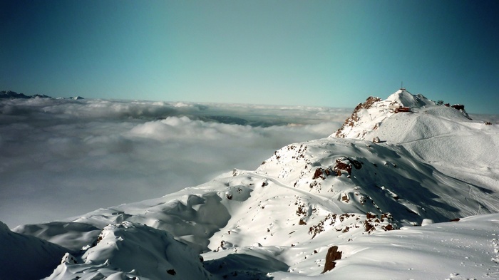 Snowy mountain peaks above the clouds in the Alps