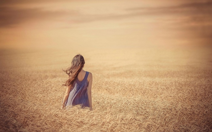 Woman in a blue dress in a wheat field