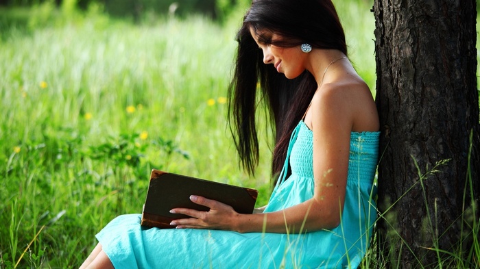 Woman reading a book under a tree