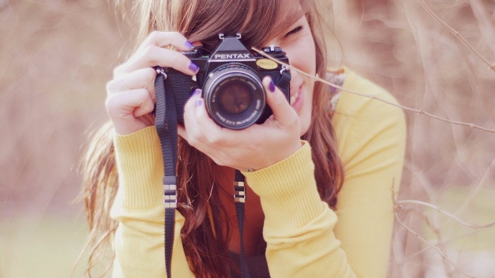 Woman holding a Pentax camera outdoors