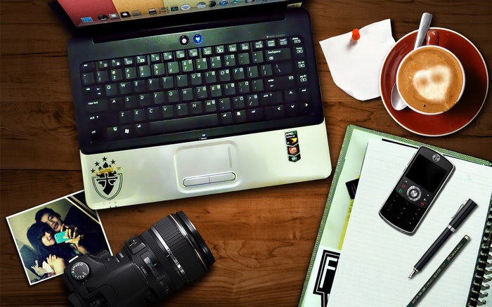 Laptop, camera, coffee, and cellphone on a wooden desk