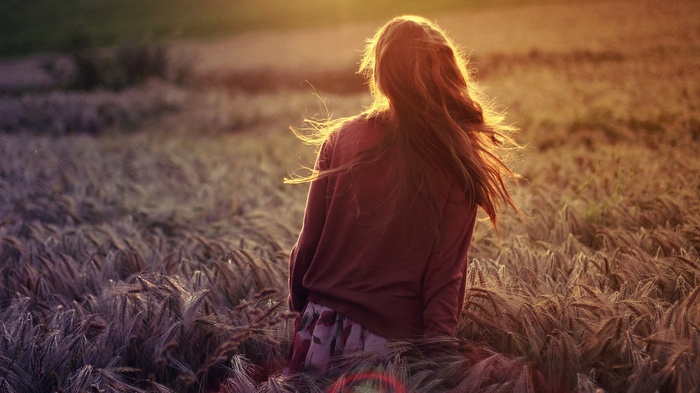 Woman with long hair in a field at sunset