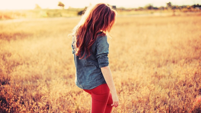 Redhead woman in a field at sunset