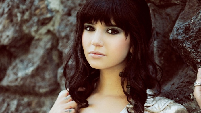 Woman with bangs and tattoos looking at viewer