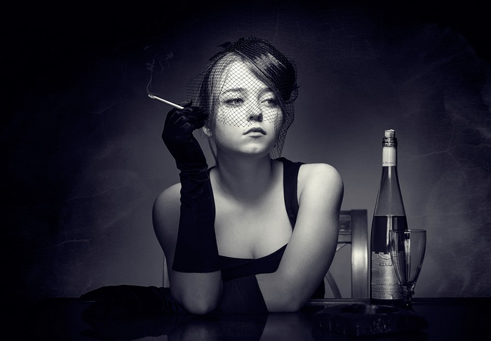 Woman in veil smoking with wine bottle