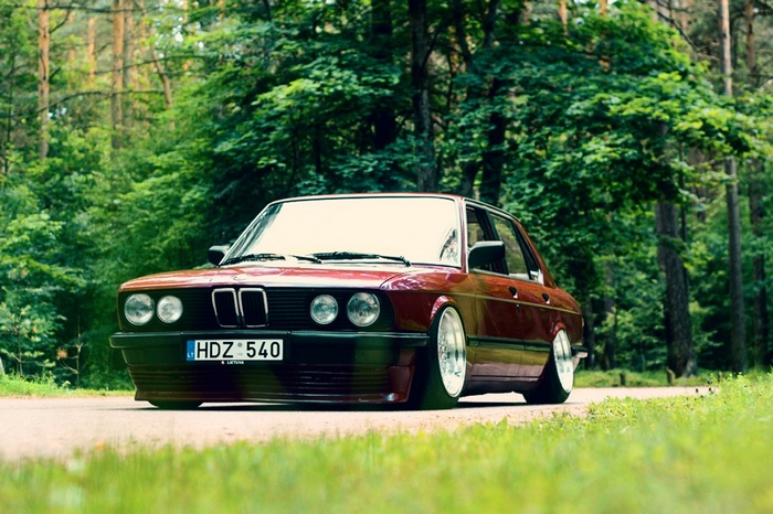 Red BMW E28 parked on a forest road