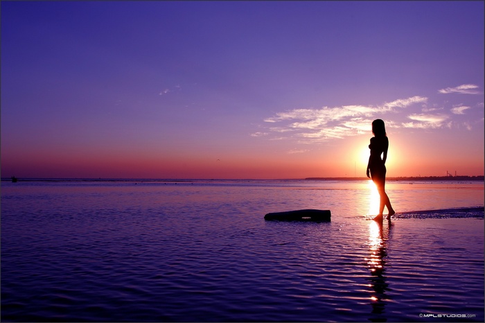 Woman silhouetted against sunset on a beach