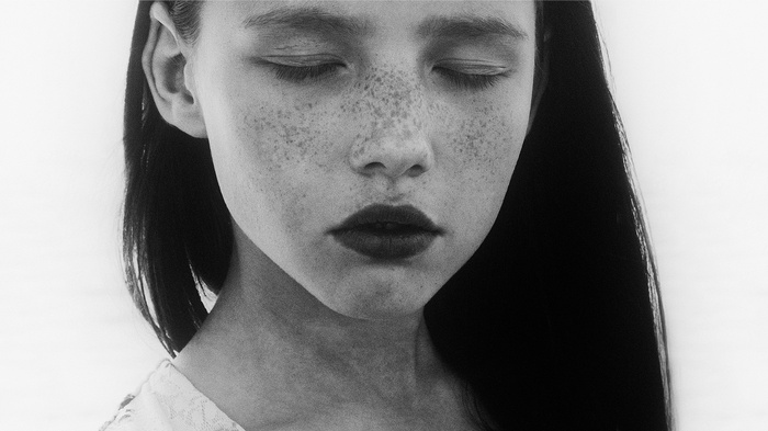 Monochrome close-up of a woman with freckles and closed eyes