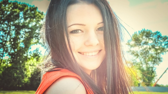 Smiling brunette woman in orange shirt outdoors