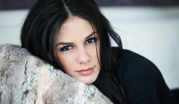 Woman with dark hair resting on a furry pillow