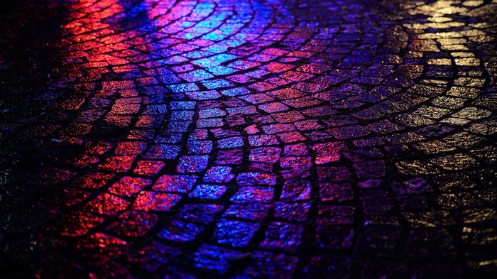 Wet cobblestone street with red and blue lights