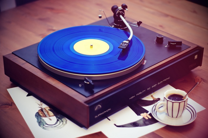 Vintage turntable playing a blue vinyl record with coffee