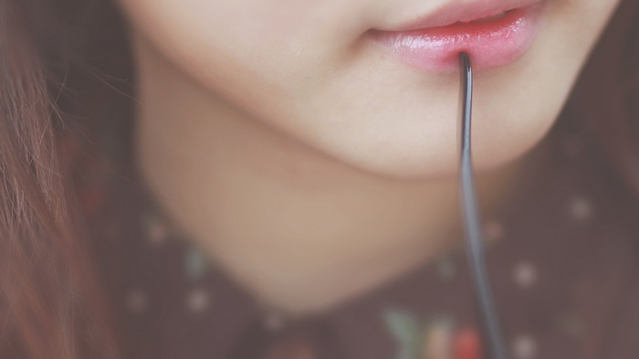 Close-up of a woman's lips with a utensil
