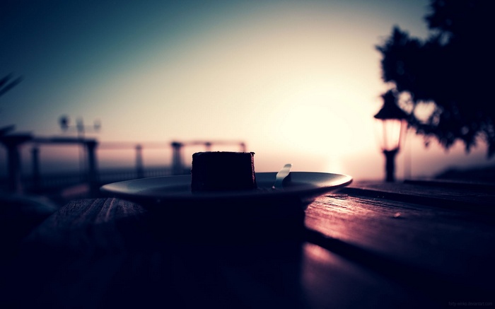 A piece of chocolate cake on a plate at sunset