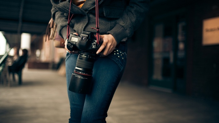 Woman holding a DSLR camera with a large lens