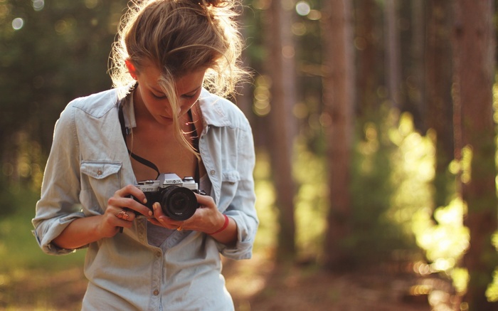 Woman holding a camera in a forest