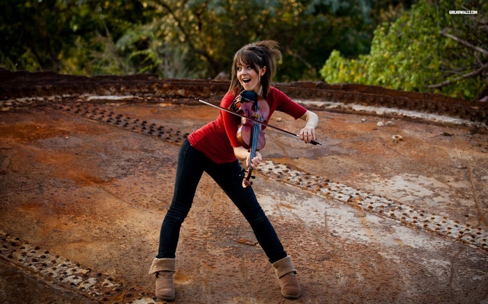 Lindsey Stirling playing violin on rusty surface