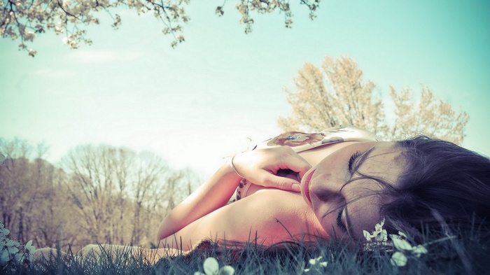 Woman lying in grass with trees in background