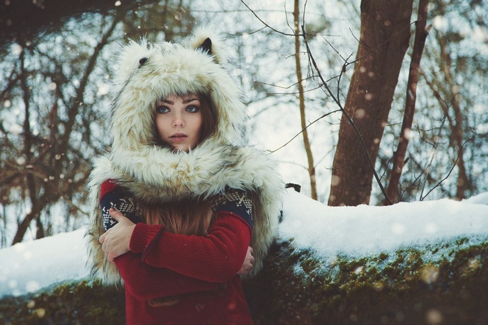 Woman in a furry hood in a snowy forest