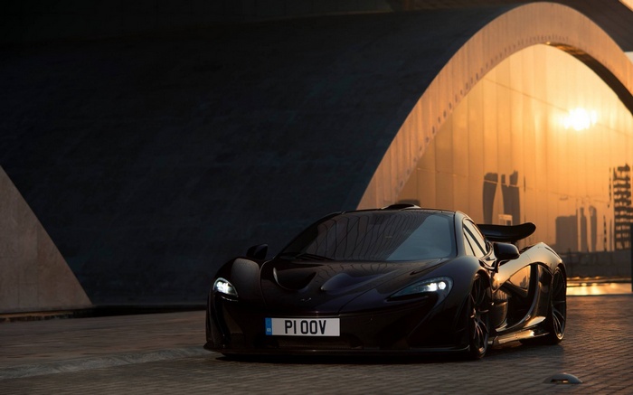 Black McLaren P1 parked under a bridge at sunset