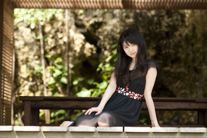 Sayumi Michishige sitting on a wooden bench outdoors