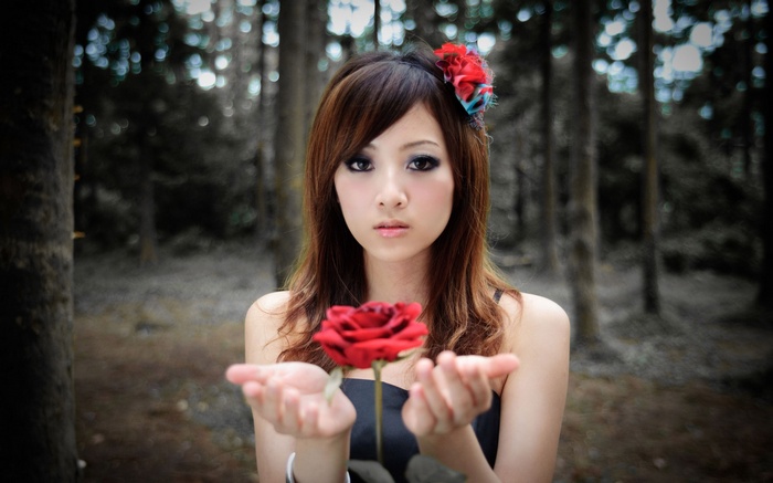 Woman holding a red rose in a forest
