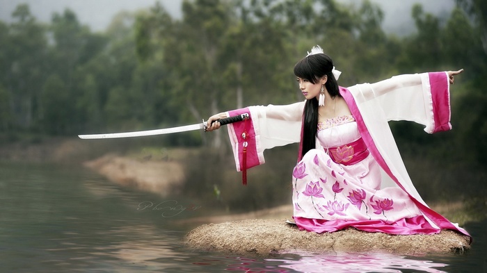 Asian woman in pink kimono with sword and lotus flowers
