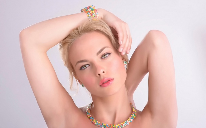 Woman with blonde hair and green eyes wearing colorful jewelry