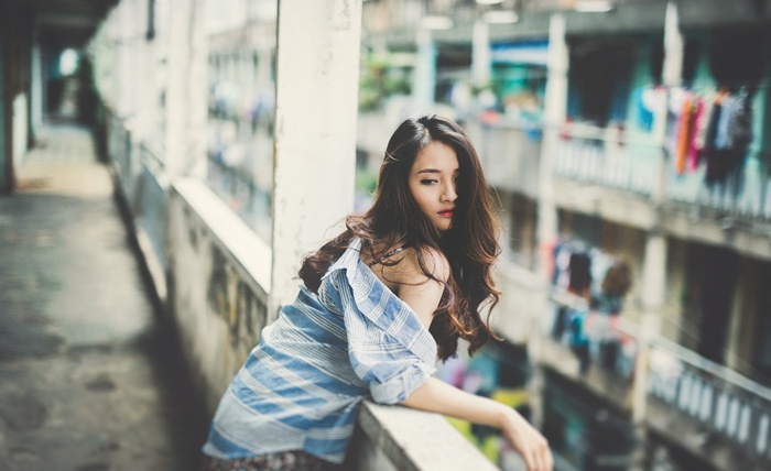 Asian woman leaning on a balcony railing