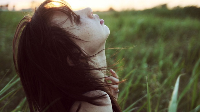 Woman with freckles in a field at sunset