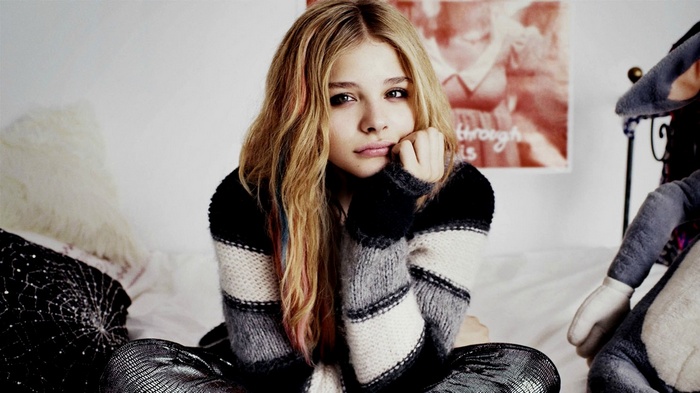 Chloë Grace Moretz sitting on a bed