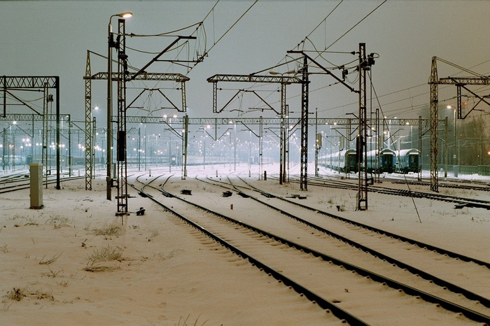 Snowy train station with overhead wires and trains