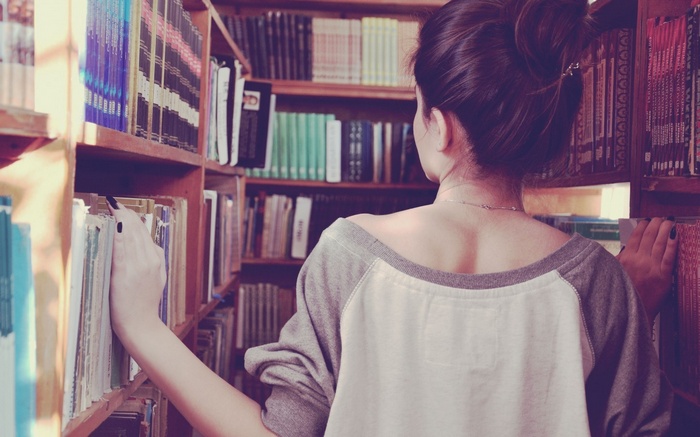 Woman with black nails browsing books in a library