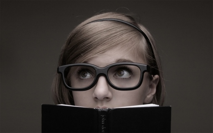 Woman wearing glasses looking up from a book