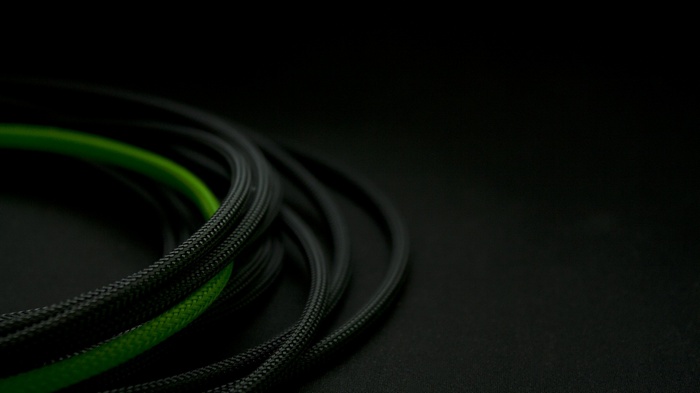 Black and green wires coiled on a dark surface