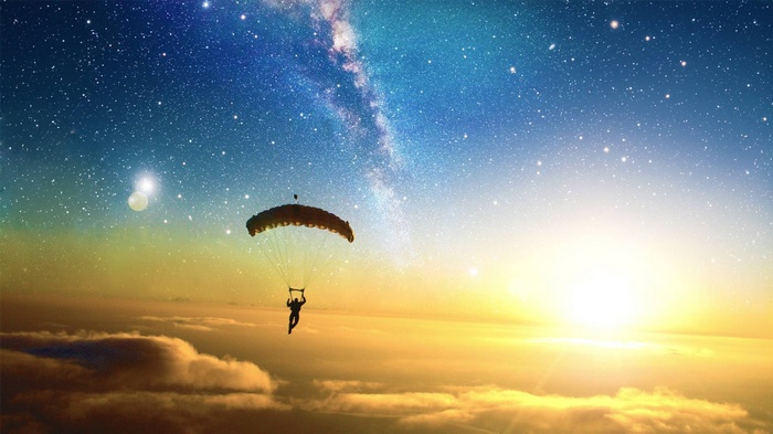 Parachutist under the Milky Way and sunrise