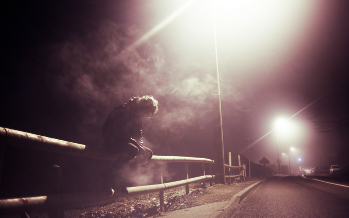 Man sitting on a guardrail at night