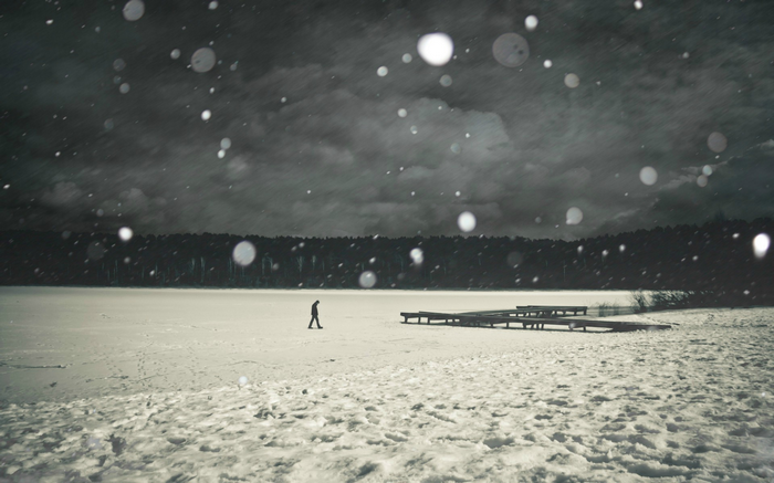 Man walking on a frozen lake during snowfall