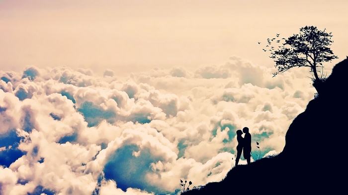 Couple kissing on a cliff above clouds with a tree