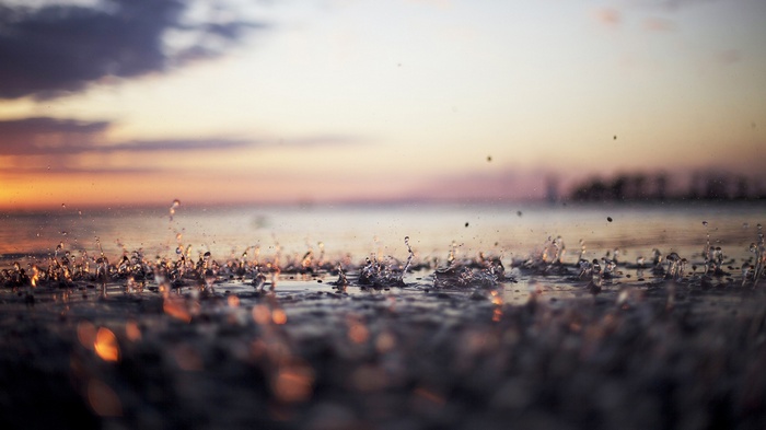 Raindrops splashing on water at sunset