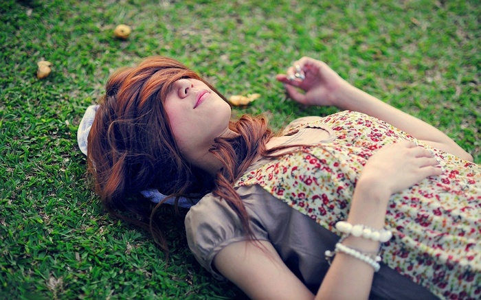Young Asian woman lying on grass with hair covering face